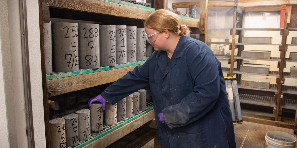 An AOT materials lab technician places concrete samples in temperature controlled misting room