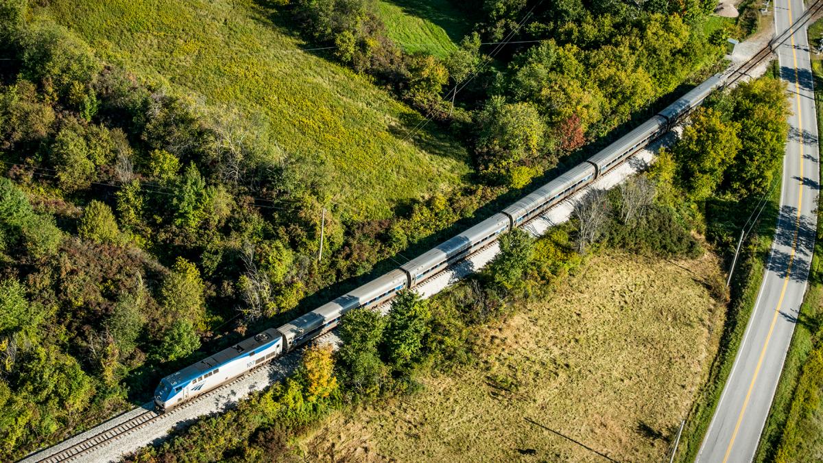 An aerial photo of an Amtrak train in motion on the rail line