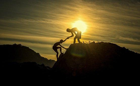 Mountain with two hikers reaching for each other