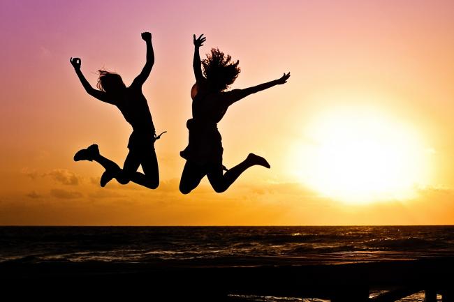 Sunset with two silhouettes jumping in mid air