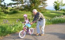 Grandfather pushing grand daughter on bike